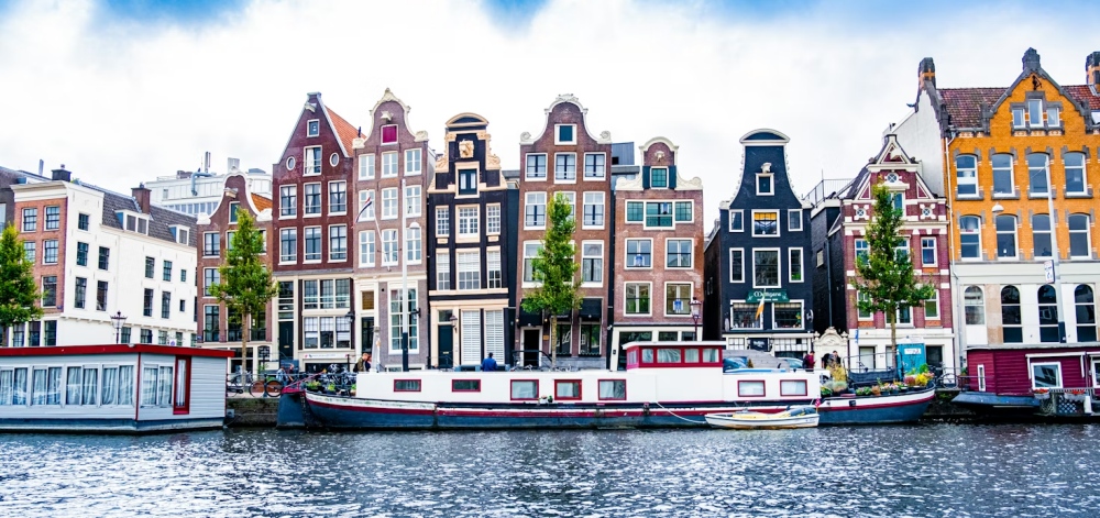 Canal houses and a white houseboat along the water in Amsterdam.