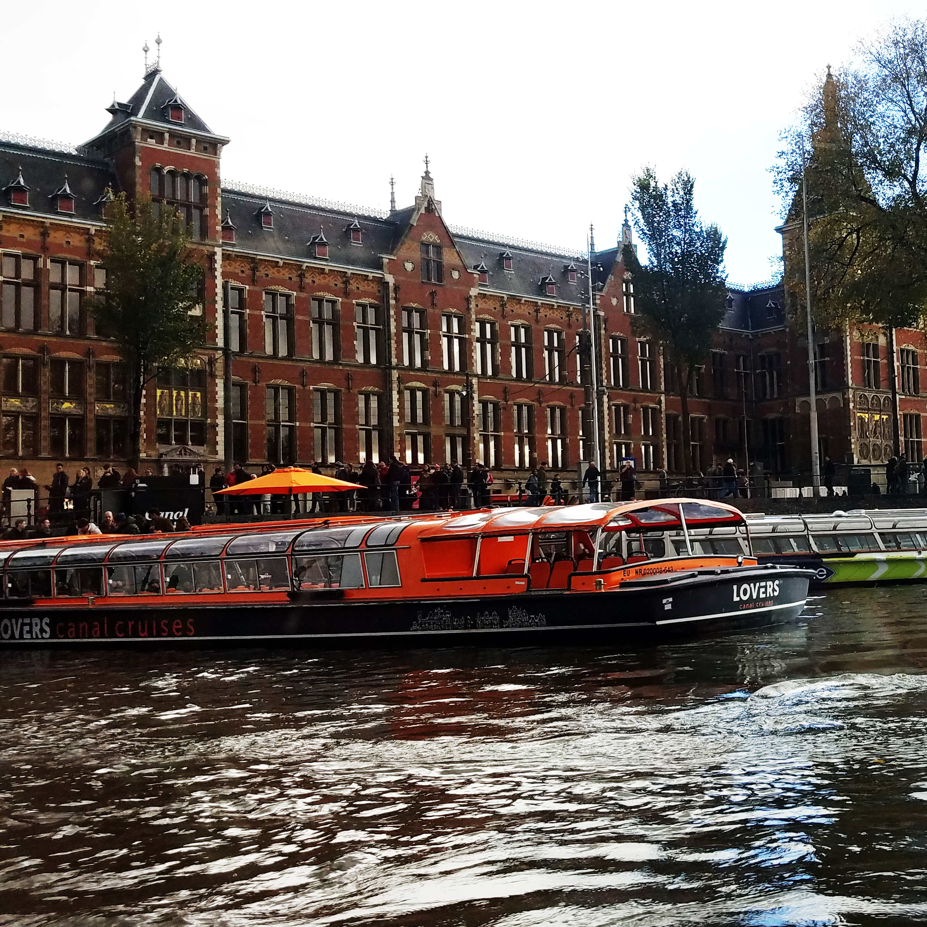 Canal cruise boats in front of historic buildings in Amsterdam.