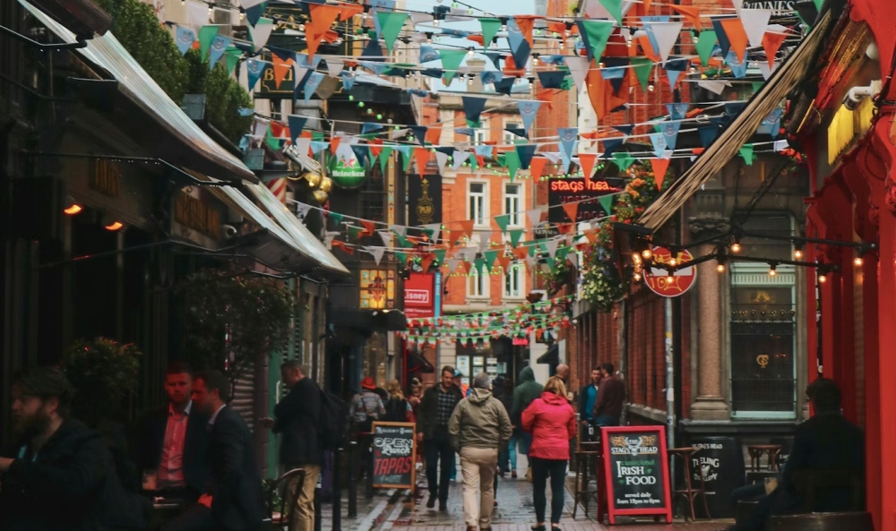 People walking along a Dublin pub lane with bunting overhead.