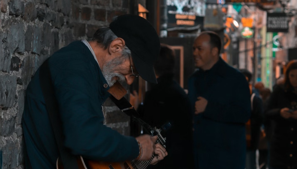 A street musician playing guitar in a Dublin lane.