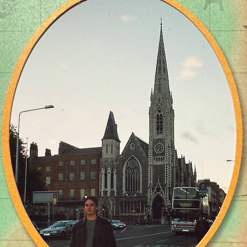 A church and passing bus framed by an archway in Dublin.