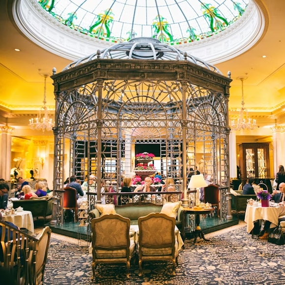 A closer view of guests seated beneath The Savoy's ornate metal gazebo and stained-glass dome.