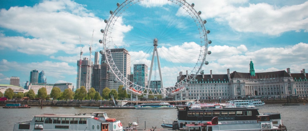 The London Eye rising above the Thames in London with river traffic below.