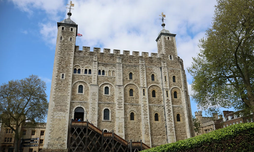 The White Tower rising behind the entrance ramp and stone walls at the Tower of London.