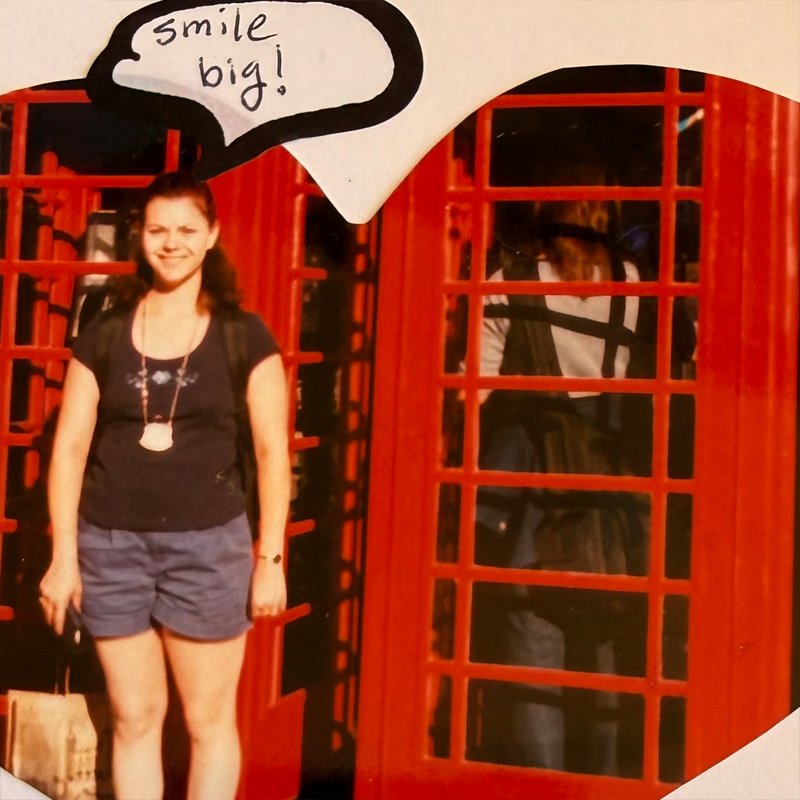 A traveler standing beside bright red London phone boxes.