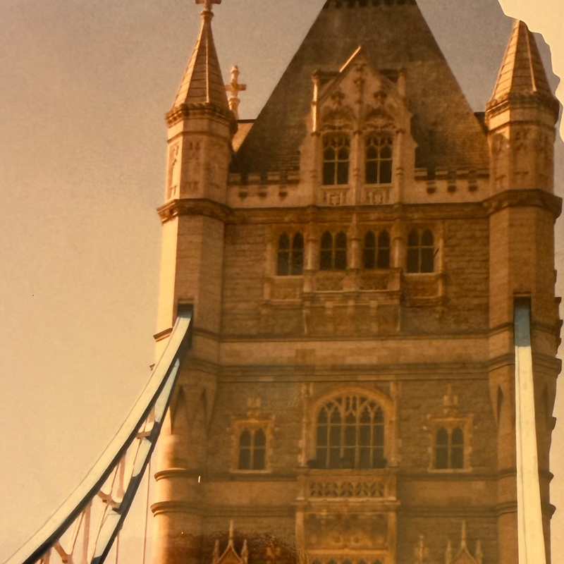 One of Tower Bridge’s stone towers and blue suspension elements seen up close.