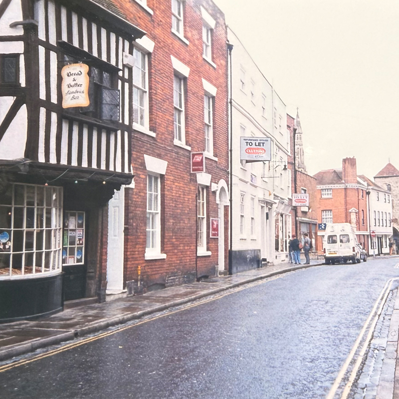 A quiet street lined with brick and half-timbered buildings on a cloudy day.