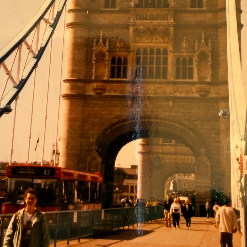 Tower Bridge with a red double-decker bus and pedestrians crossing it in London.
