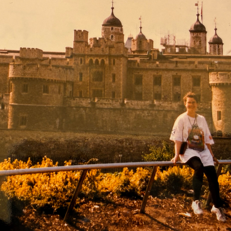 A traveler sitting near the Tower of London with the fortress in the background.