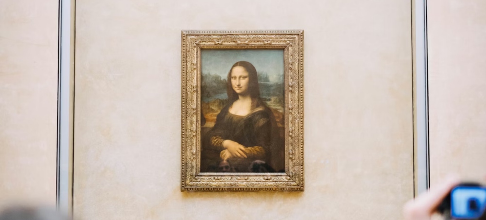 The Mona Lisa hanging on a wall at the Louvre with visitors below.