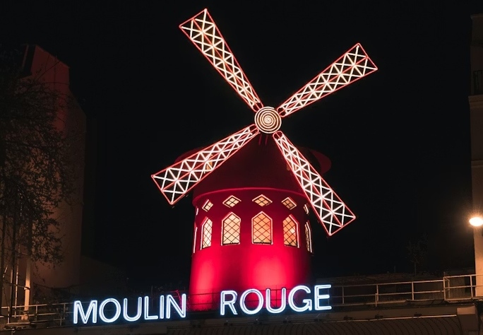 The red-lit Moulin Rouge windmill at night.