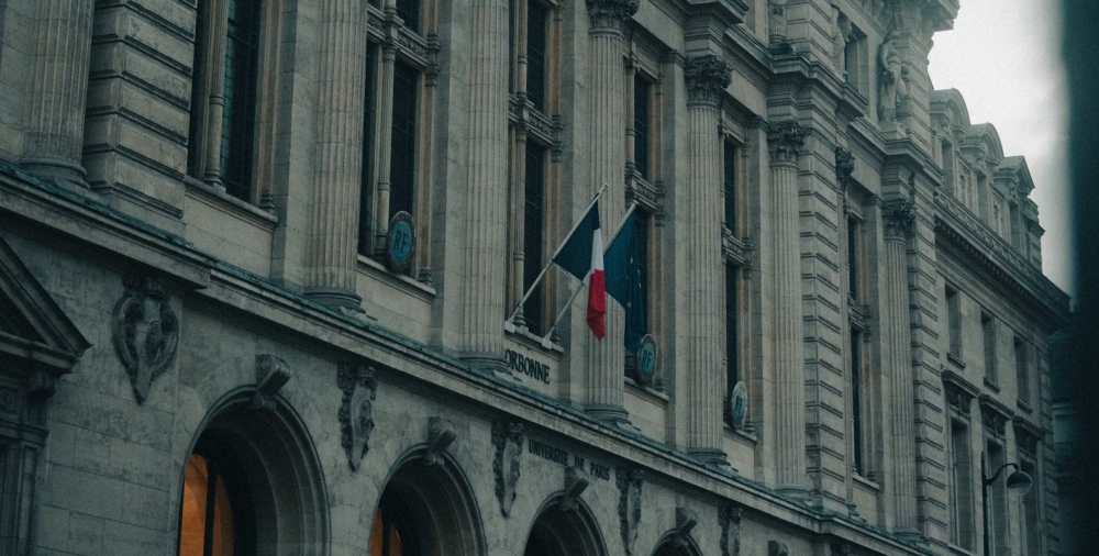 The stone facade of the Sorbonne with tall columns and a French flag above the entrance.