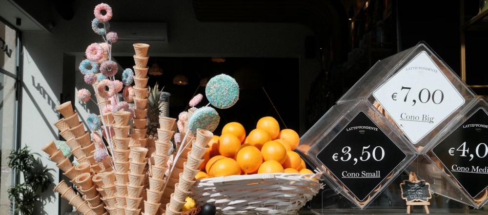 Gelato cones, oranges, and price signs outside a shop in Rome.