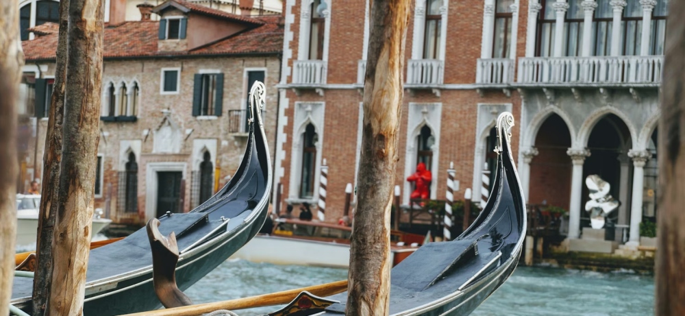 Two gondola prows tied beside canal posts in Venice.